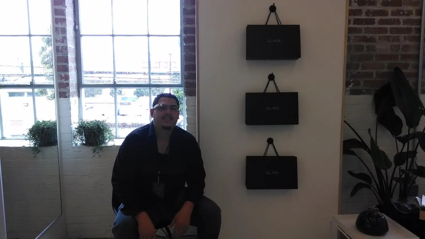 William wearing Google Glass beside Glass display bags